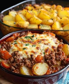 a casserole dish with potatoes and meat in it on a wooden table next to another casserole dish