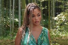 a woman with long hair standing in front of bamboo trees and looking at the camera