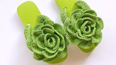 a pair of green flip flops with a flower on the bottom and one in the middle