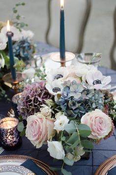 the table is set with candles and flowers on it, along with other place settings