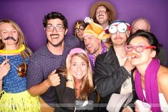 a group of people standing next to each other posing for a photo booth with fake mustaches on their mouths