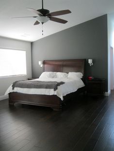 a bed sitting in a bedroom next to a window with a fan on top of it