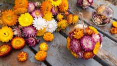 colorful flowers are arranged on an old wooden bench for display or to be used as centerpieces