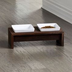 two white bowls with food in them sit on a wooden table next to each other