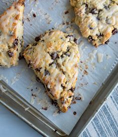 four scones sitting on top of a pan covered in chocolate chips and coconut flakes