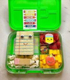 a green lunch box filled with lots of different foods and decorations on it's lid