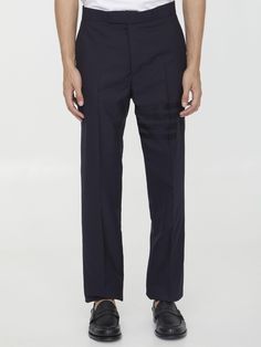 Straight-leg pleated trousers in navy blue wool with 4-Bar detail on left leg. It features button and hook closure, two side welt pockets, two rear buttoned welt pockets and adjustable backstrap detail. Tricolor grosgrain loop tab detail at the back. Regular fit. The model is 190cm tall and wears size 02.  Size nationality: US  Product number: 3515625  Product code: MTC001A06146420  Composition: 100% WOOL Formal Navy Bottoms With Welt Pockets, Navy Formal Bottoms With Welt Pockets, Classic Navy Dress Pants With Welt Pockets, Tailored Classic Navy Pants, Navy Business Bottoms With Welt Pockets, Navy Tapered Leg Dress Pants For Formal Occasions, Tailored Navy Dress Pants With Welt Pockets, Navy Tailored Dress Pants With Welt Pockets, Classic Navy Pants With Belt Loops