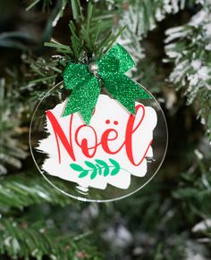 a glass ornament hanging from a christmas tree with the word noel on it