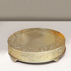 an ornately decorated gold plate sits on a white surface