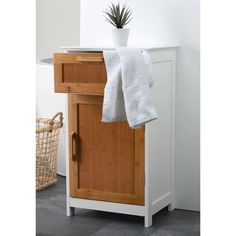 a white towel is hanging on a cabinet with a potted plant in the corner