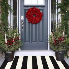 a front door decorated with christmas wreaths and potted plants