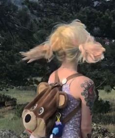 a woman with blonde hair carrying a stuffed animal