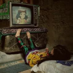 a woman laying on the ground in front of a tv with an image of snow white on it