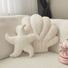 a stuffed animal is sitting on a white couch next to a pink vase with flowers