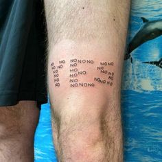 a man with a tattoo on his leg that has words written all over it and dolphins in the background