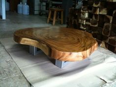 a large wooden table sitting on top of a white floor next to stacks of logs