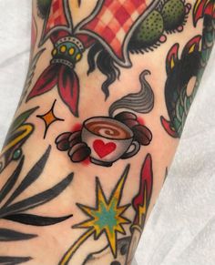 a person with tattoos on their arm holding a coffee cup and saucer in the shape of a heart