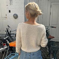 a woman is standing in front of some bikes and looking at the back of her sweater