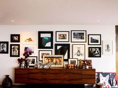 an image of a wall with many pictures on it and a dresser in the foreground