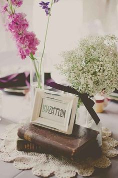 a vase filled with purple flowers sitting on top of a table next to an old book