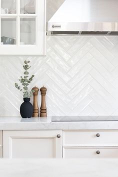 a kitchen with white cabinets and a black vase sitting on the counter next to it