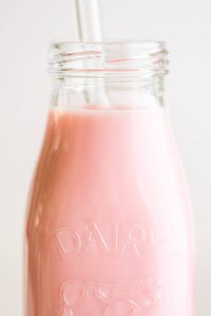 a glass jar filled with pink liquid and a straw