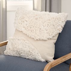 a white pillow sitting on top of a blue couch next to a wooden arm chair