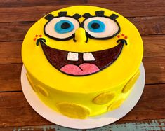 a yellow cake with blue eyes and an angry expression on it's face is sitting on a wooden table