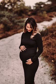 a pregnant woman standing on a dirt road