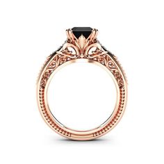 a rose gold engagement ring with an intricate design and black diamonds on the side, set in