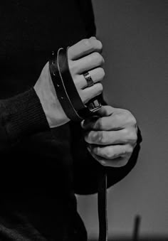 black and white photograph of a person's hand holding a cell phone with wristbands