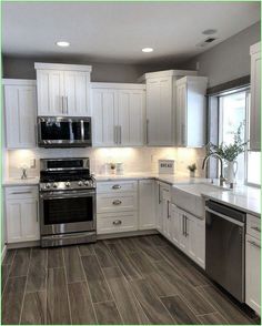 a large kitchen with white cabinets and stainless steel appliances, including an oven, dishwasher, microwave, stove and sink