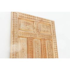 an intricately carved wooden door is displayed on the wall in front of a white wall