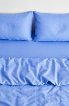 a bed with blue sheets and pillows on it