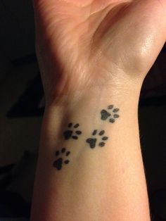 a person with a small tattoo on their wrist that has paw prints all over it