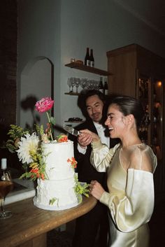 a bride and groom are cutting their wedding cake at the table in front of them