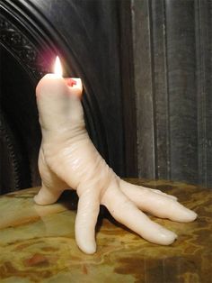 a fake hand holding a lit candle on top of a table