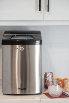 a stainless steel ice bucket sitting on top of a counter next to a can of soda