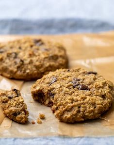 three oatmeal cookies sitting on top of a piece of waxed paper