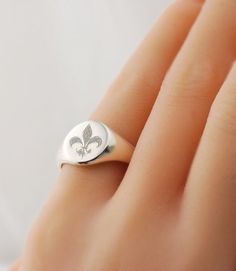 Fleur-de-lis Custom engraved signet ring in pure sterling silver. * Choose from various US ring sizes * Solid .925 Sterling Silver ~ Hallmarked * Made in the U.S.A. * Features a signet pad that measures approximately 11 x 9 mm for personalization (varies by ring size) PERSONALIZATION OPTIONS ✤ Can be engraved with any other design, logo or symbol too ❤ ☯ ✡ ✞ ★ (ask me how). ✤ Monogram with initials >> https://www.etsy.com/listing/125136982 IMPORTANT Please be sure to know your exact ring s Flower Logos, Family Crests, Fingerprint Jewelry, Signet Rings, Silver Signet Ring, Flower Logo, Themed Jewelry, Engraved Rings, Signet Ring