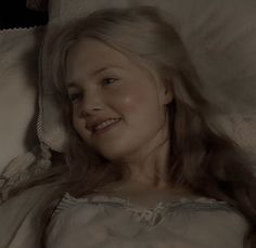 a woman laying in bed smiling at the camera