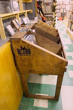 a row of wooden tables with books on them in a room filled with yellow shelves