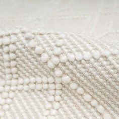 a close up view of a white blanket with small balls on it's edges