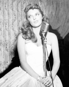 an old photo of a woman sitting in front of a microphone with her hair blowing back