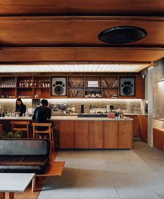 two people are sitting at the bar in this modern kitchen with wood cabinets and counter tops