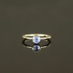 two stone ring sitting on top of a black surface with the reflection of it's face