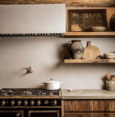 a kitchen with an oven, stove and shelves filled with pots and pans on top of it