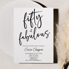 a white card with black lettering on it and a feather next to it that says fifty and fabulous