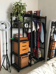 an organized closet with clothes, baskets and other items on shelves next to a bed