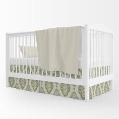 a white crib with a blanket on top of it and a sheet hanging from the rail